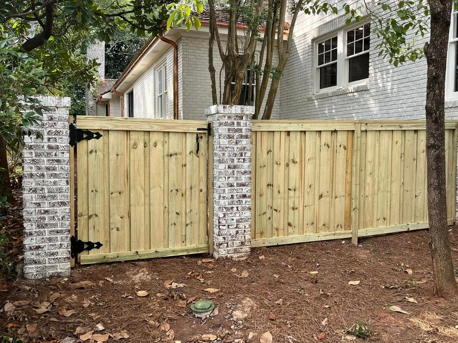 Custom wood fence and gate between brick pillars by Spartan Fence SC in Reidville, SC